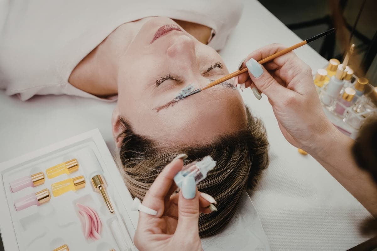 Woman receiving a brow tinting treatment at a beauty salon with a brush