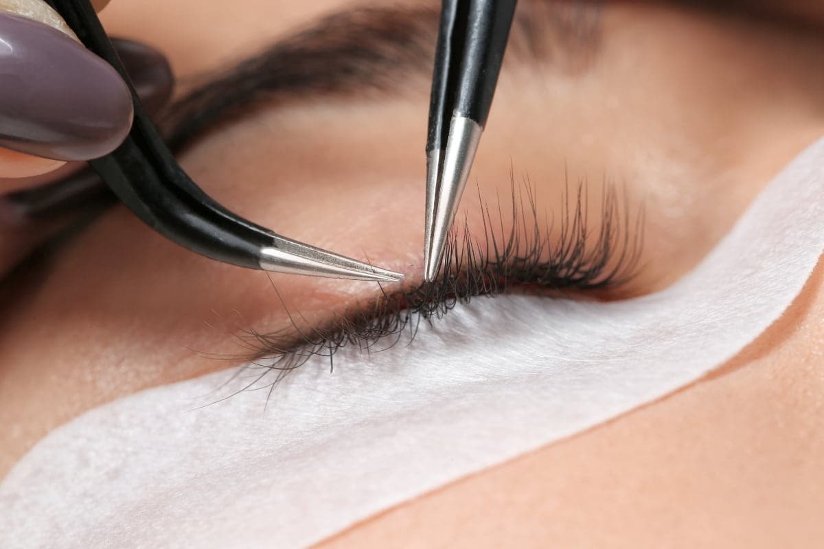 Young woman undergoing an eyelash extensions procedure, closeup