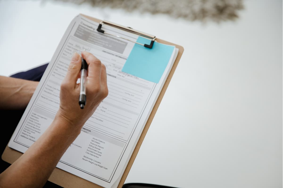 Client writing their details on a printed lash extension consent form at a lash studio before an appointment