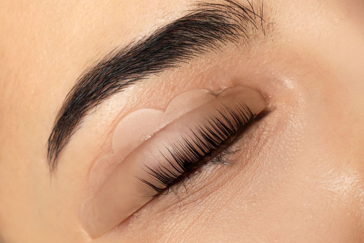 Close-up of a young woman undergoing an eyelash extension procedure in a professional setting