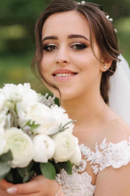 Bride with volume lash extensions smiling and holding a white bouquet on her Florida wedding day
