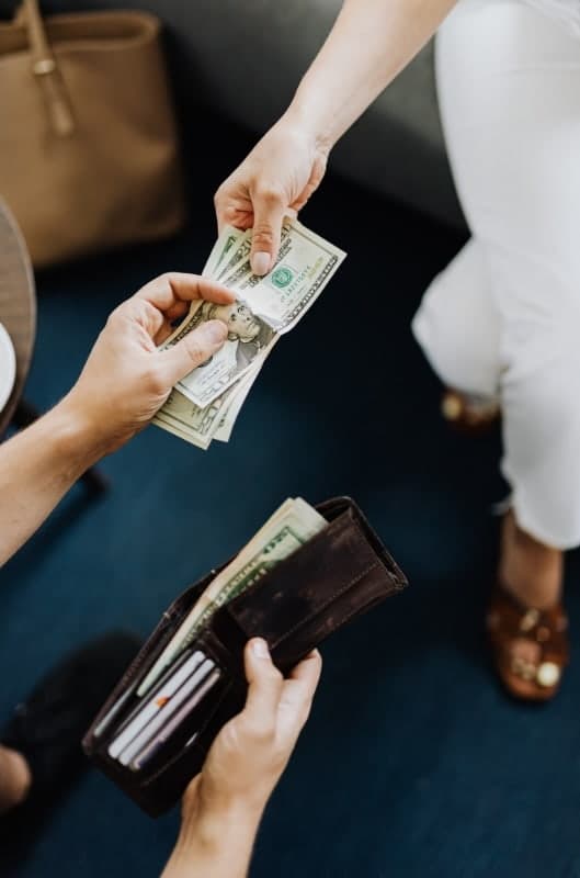 Client handing cash deposit to a lash tech before an appointment