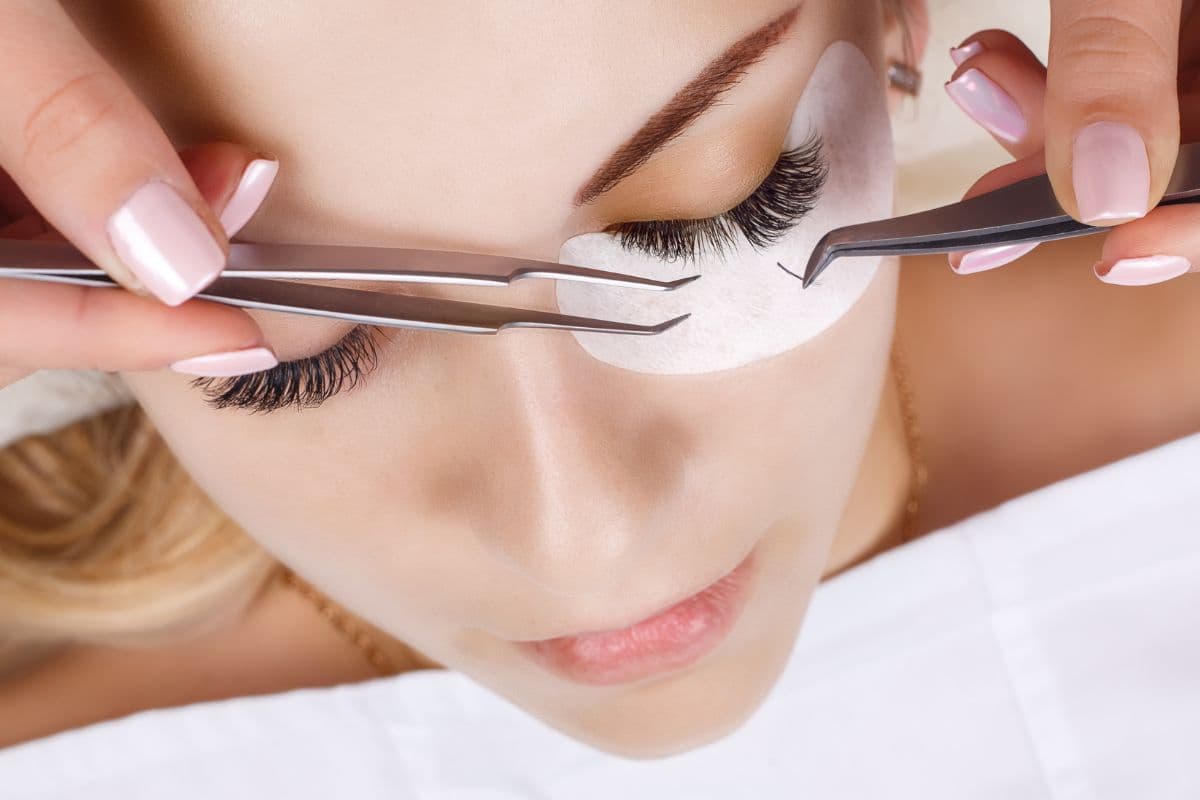 Lash artist applying eyelash extensions to a client during a full set appointment