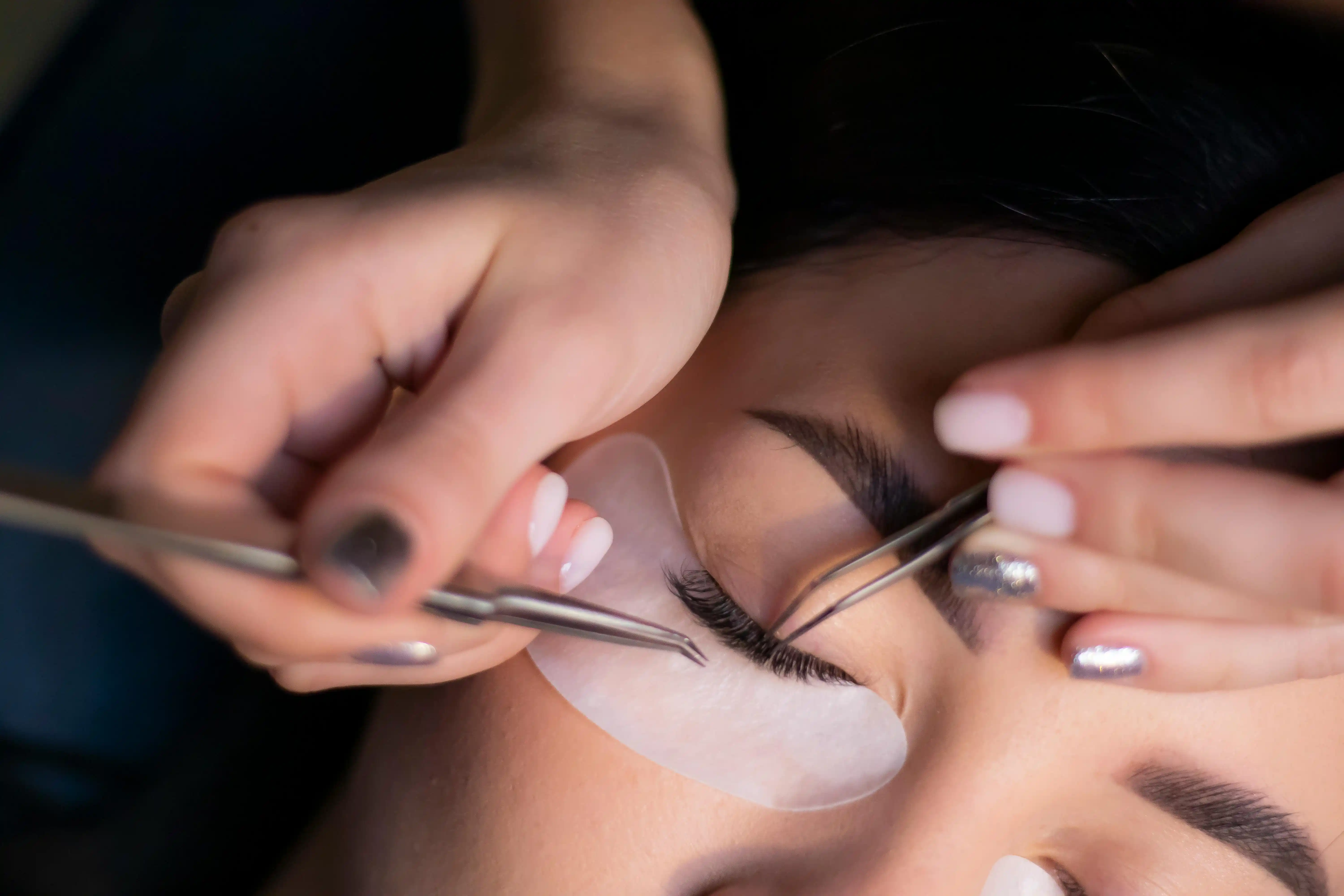 Lash extension treatment appointment Lash artist applying lash extensions during a treatment appointment